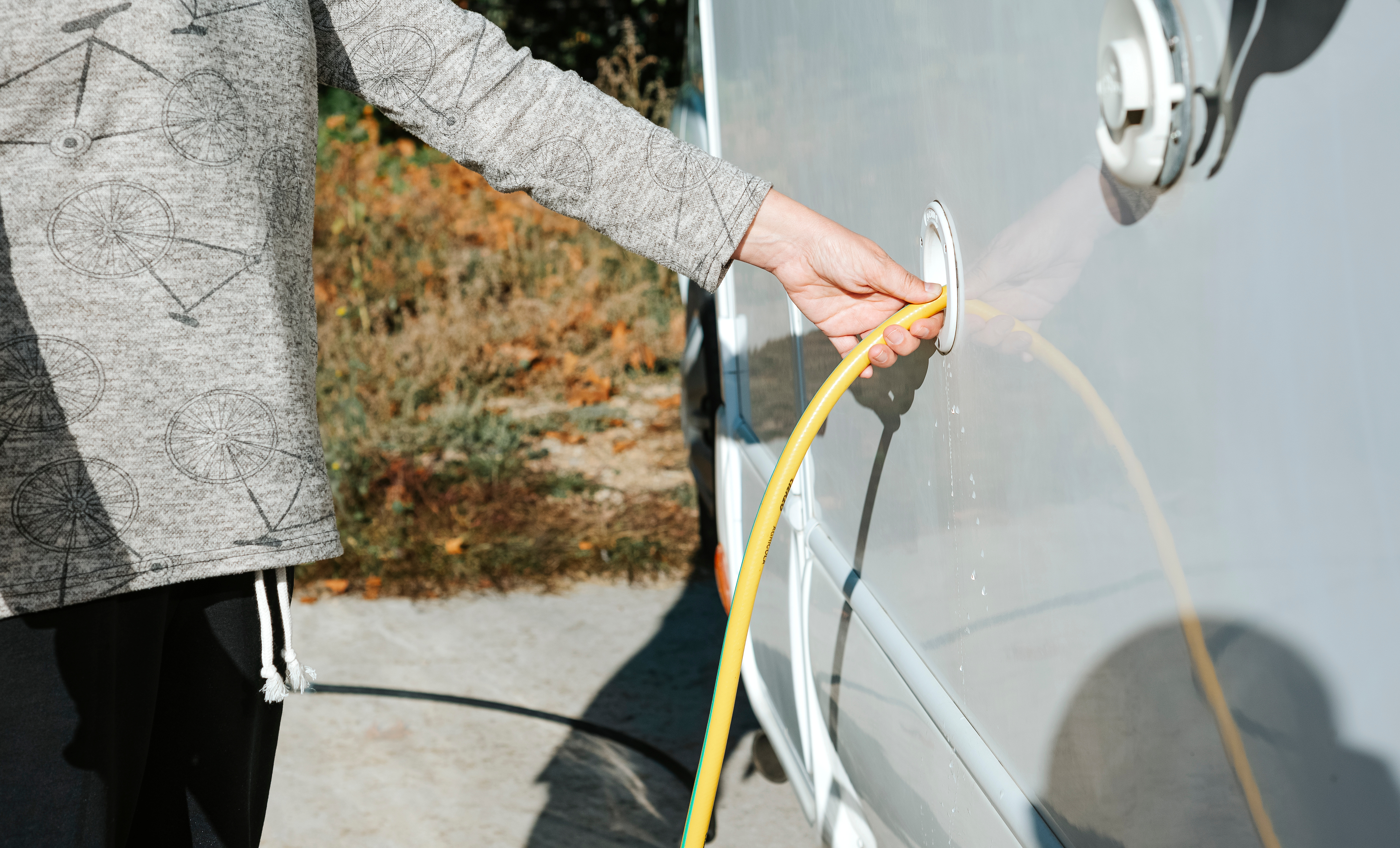 close-up of a woman's hand filling the water tank of a motorhome